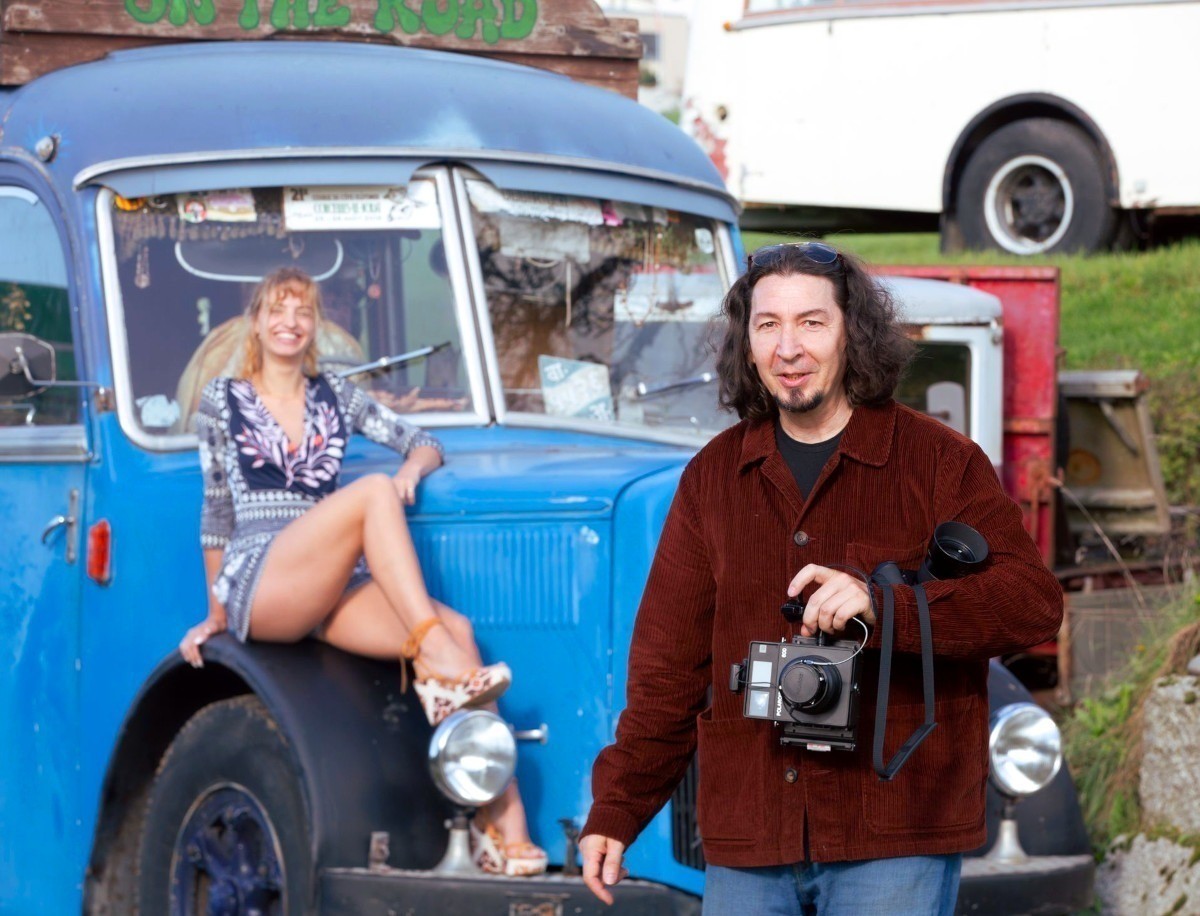 Personne posant sur une voiture ancienne, avec le photographe en premier plan.