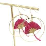 Ginko leaf earrings framed with two golden hoop earrings.