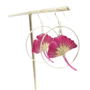 Ginko leaf earrings framed with two golden hoop earrings.
